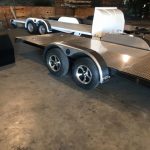 Enclosed garage with two flatbed car trailers parked side by side on a concrete floor.